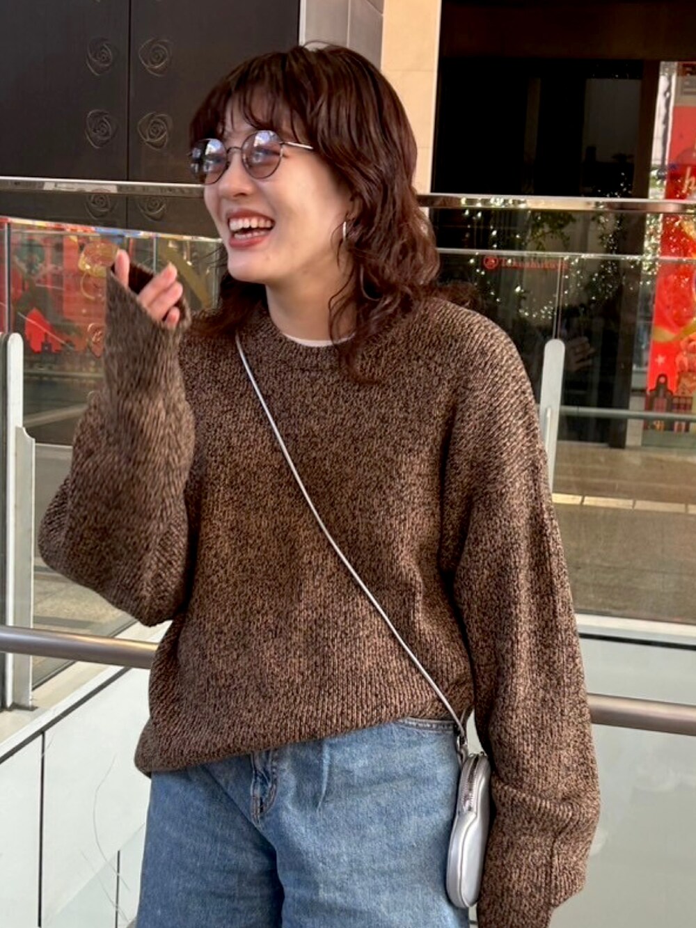 ブラウン系のニット/セーター、ブルー系のデニムパンツ、シルバー系のショルダーバッグを着用したレディースの秋コーディネートの5枚目の写真