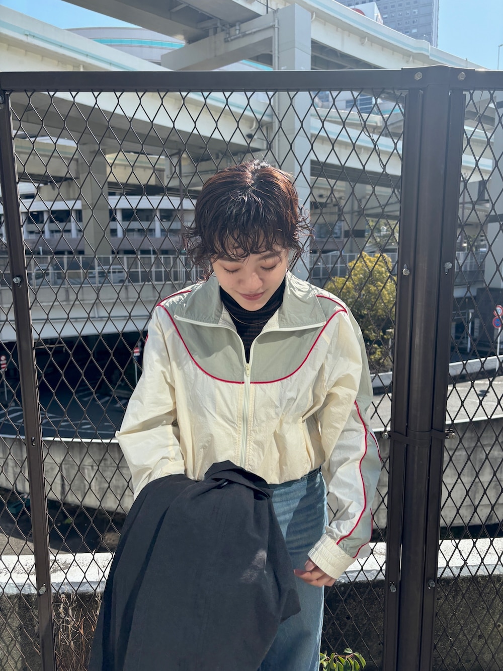 ブラック系のステンカラーコート、ホワイト系のブルゾンを着用したレディースの冬コーディネートの6枚目の写真