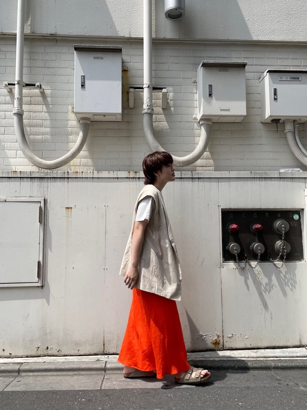 ホワイト系のベスト、ホワイト系のTシャツ/カットソー、オレンジ系のスカートを着用したレディースの夏コーディネートの5枚目の写真
