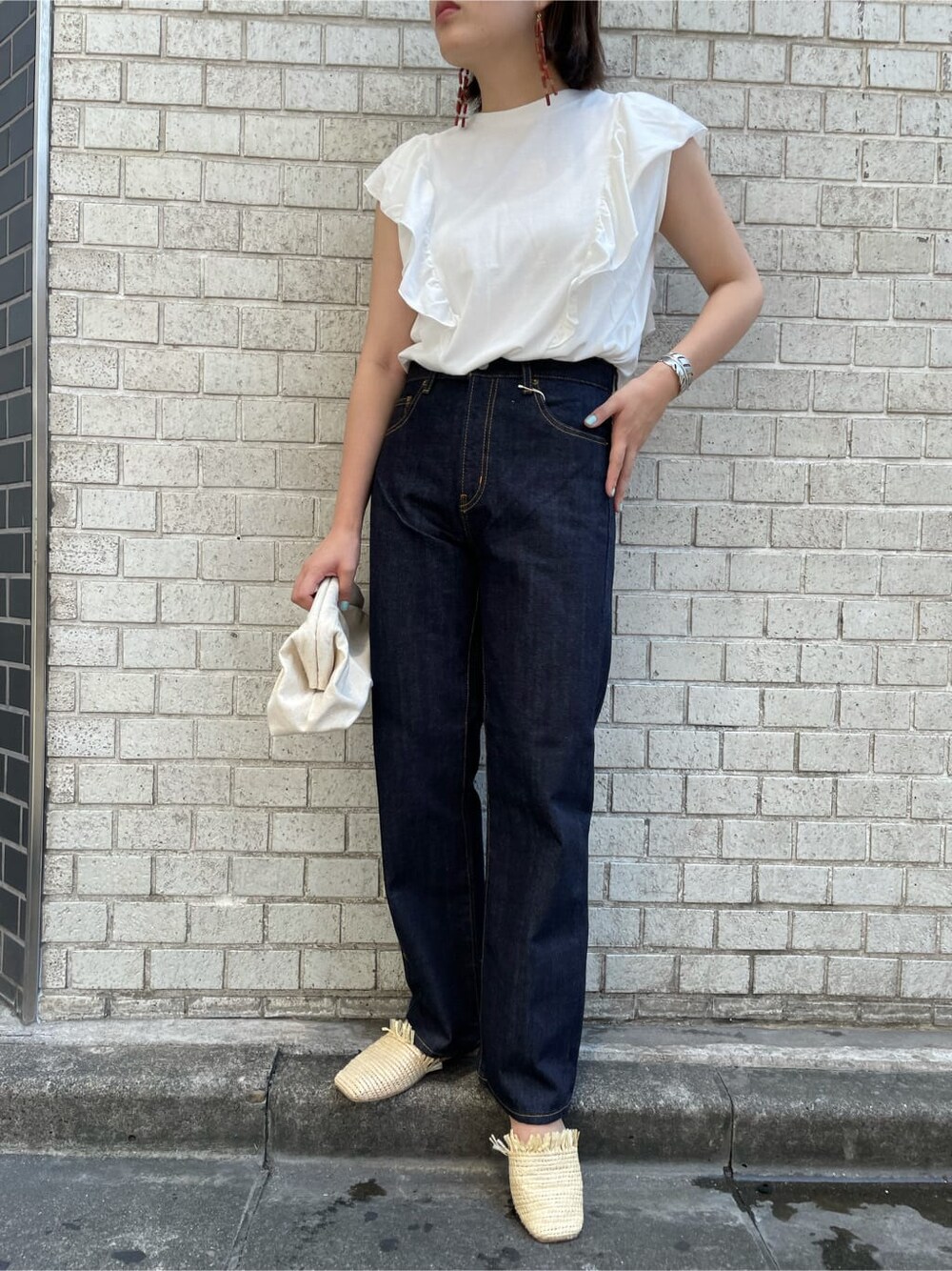 ブルー系のデニムパンツ、ホワイト系のクラッチバッグ、ホワイト系のTシャツ/カットソーを着用したレディースの夏コーディネートの5枚目の写真