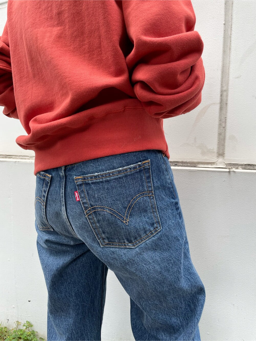 ブルー系のデニムパンツ、レッド系のスウェット、ホワイト系のハットを着用したレディースの夏コーディネートの3枚目の写真