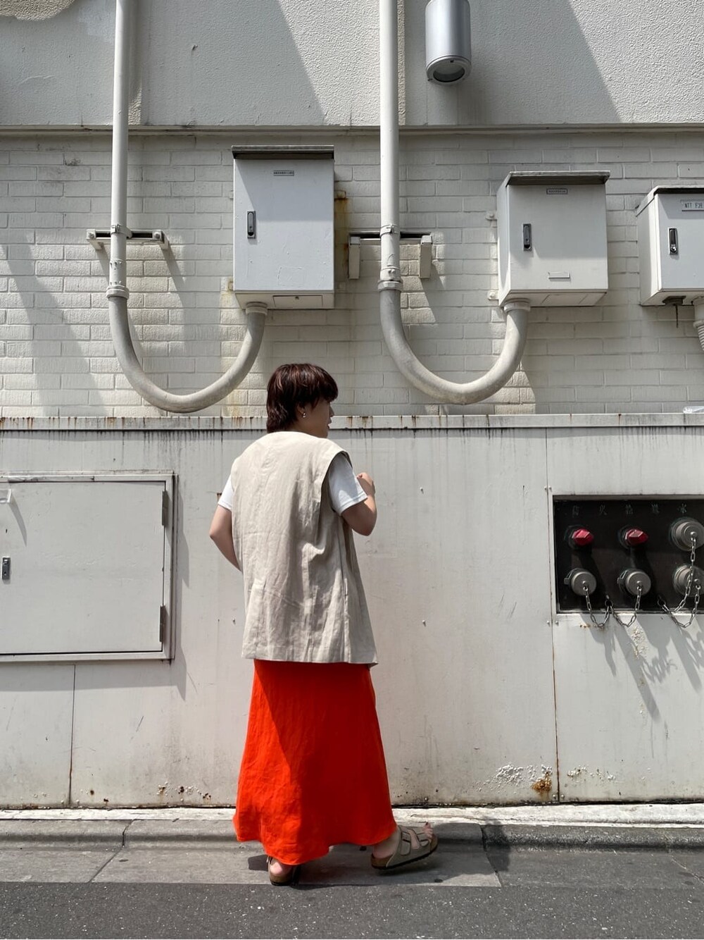 ホワイト系のベスト、ホワイト系のTシャツ/カットソー、オレンジ系のスカートを着用したレディースの夏コーディネートの6枚目の写真