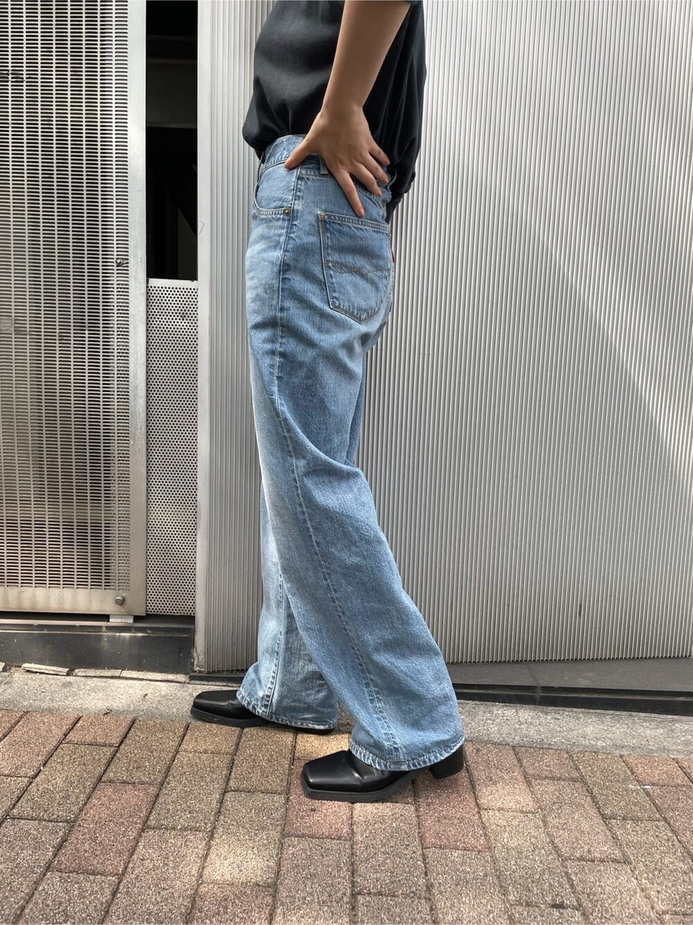 ブラック系のTシャツ/カットソー、ブルー系のデニムパンツ、ブラック系のブーツを着用したレディースの夏コーディネートの5枚目の写真