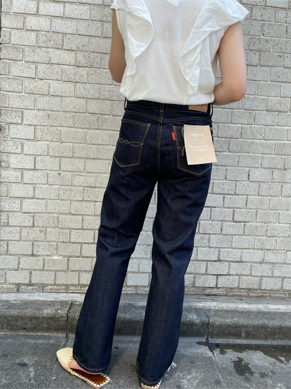 ブルー系のデニムパンツ、ホワイト系のクラッチバッグ、ホワイト系のTシャツ/カットソーを着用したレディースの夏コーディネートの6枚目の写真