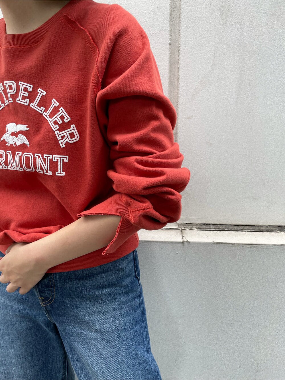 ブルー系のデニムパンツ、レッド系のスウェット、ホワイト系のハットを着用したレディースの夏コーディネートの2枚目の写真