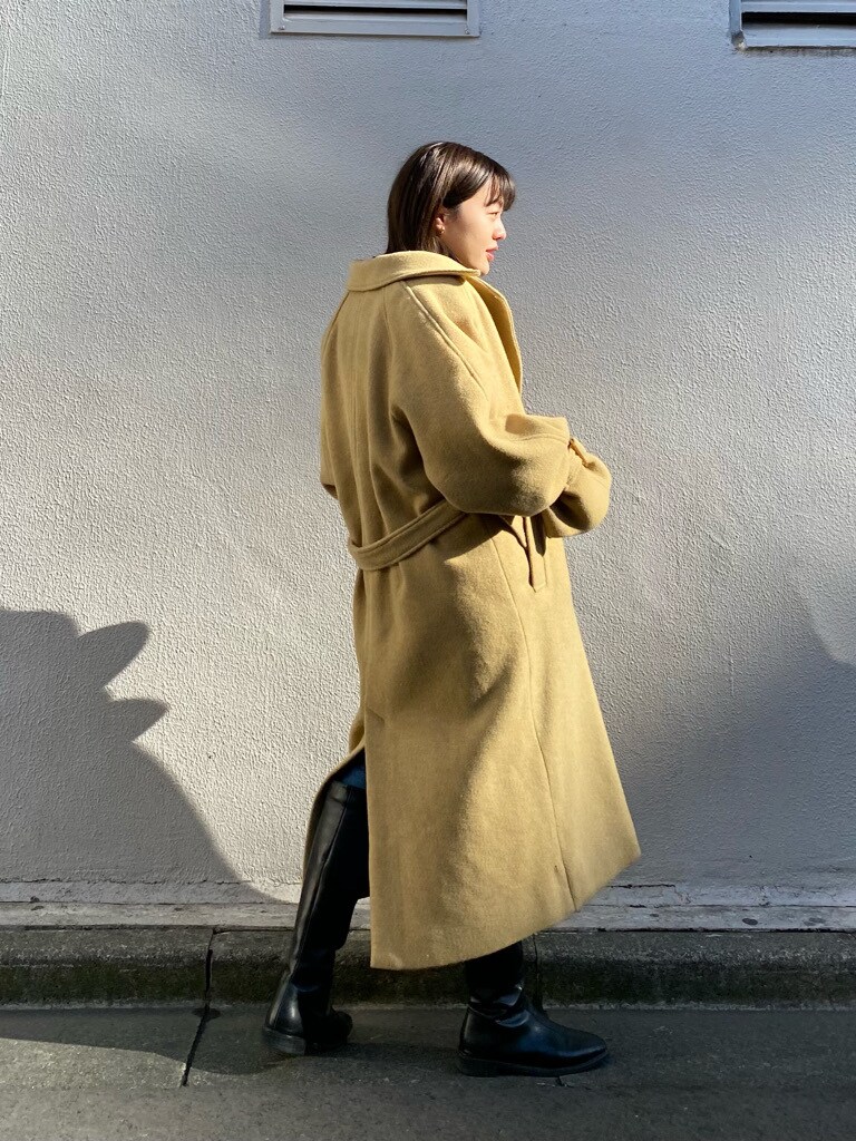 イエロー系のステンカラーコートを着用したレディースの冬コーディネートの2枚目の写真