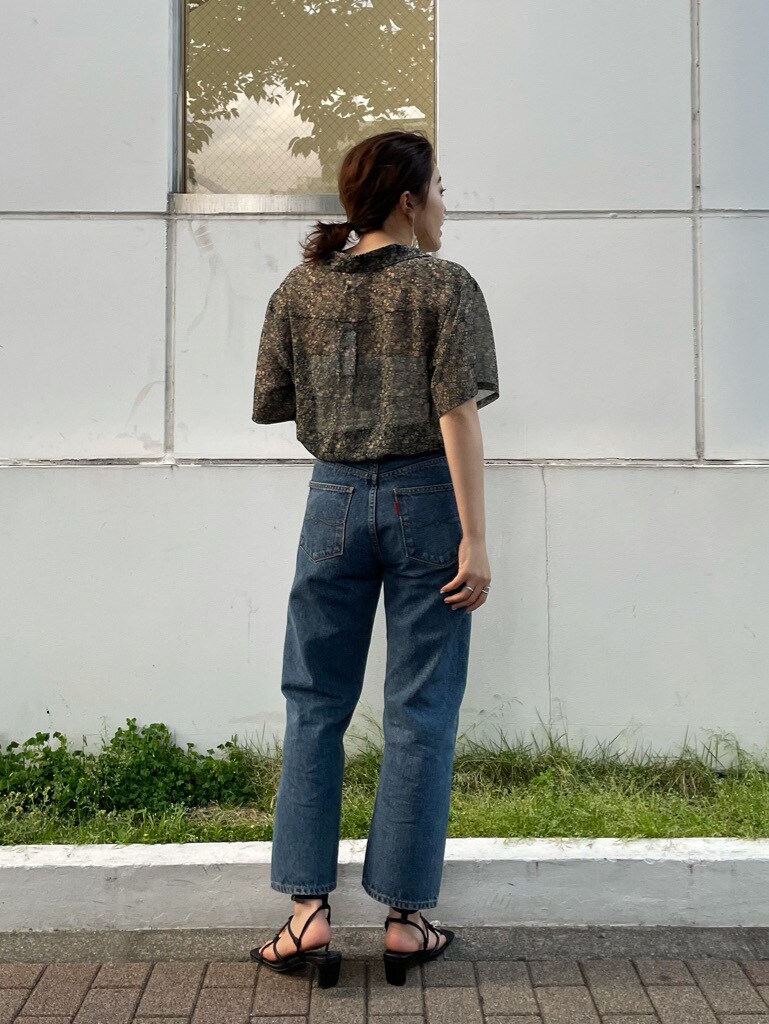 ブルー系のデニムパンツ、レッド系のシャツ/ブラウス、ブラック系のサンダルを着用したレディースの春コーディネートの2枚目の写真