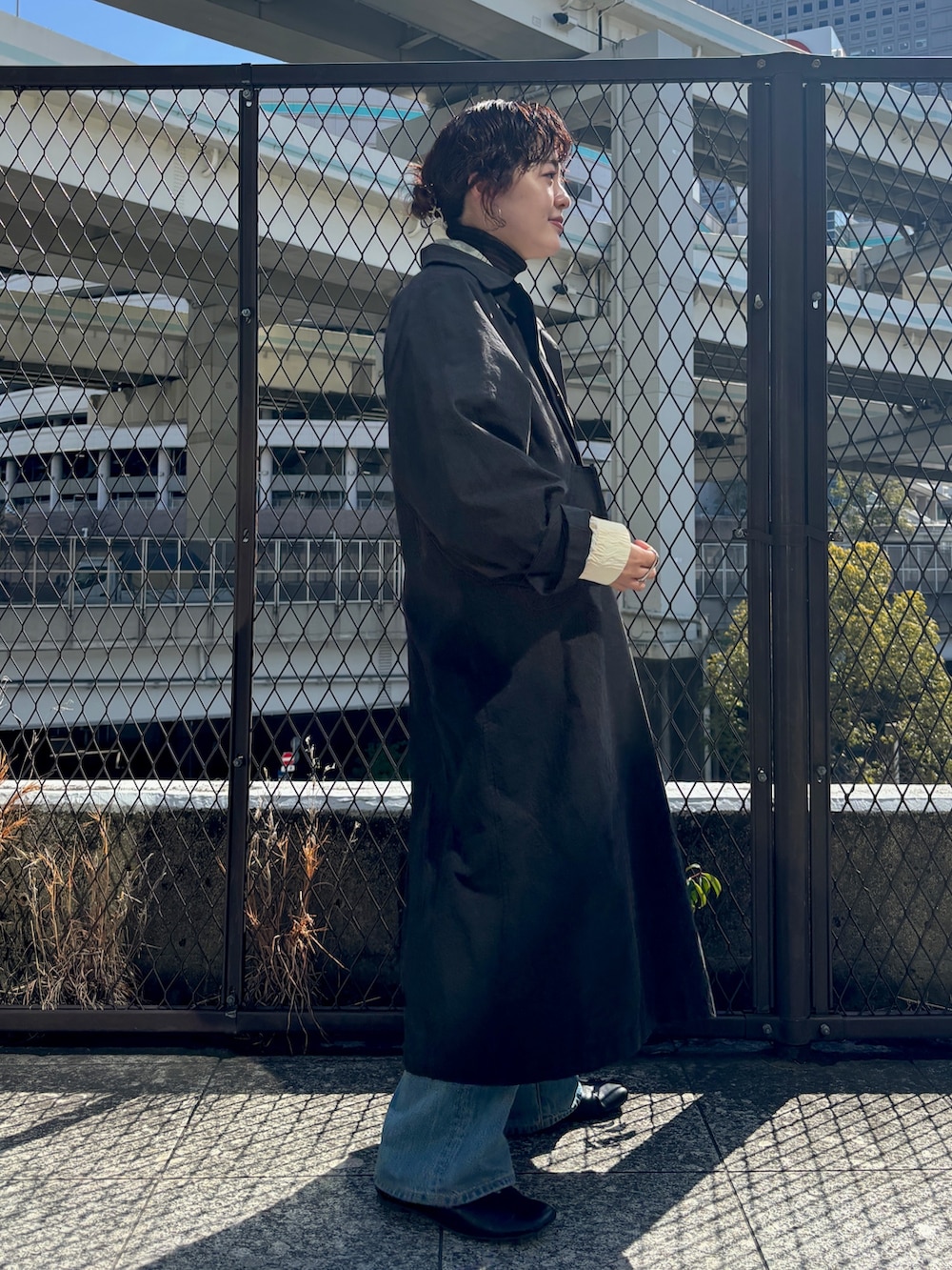 ブラック系のステンカラーコート、ホワイト系のブルゾンを着用したレディースの冬コーディネートの2枚目の写真