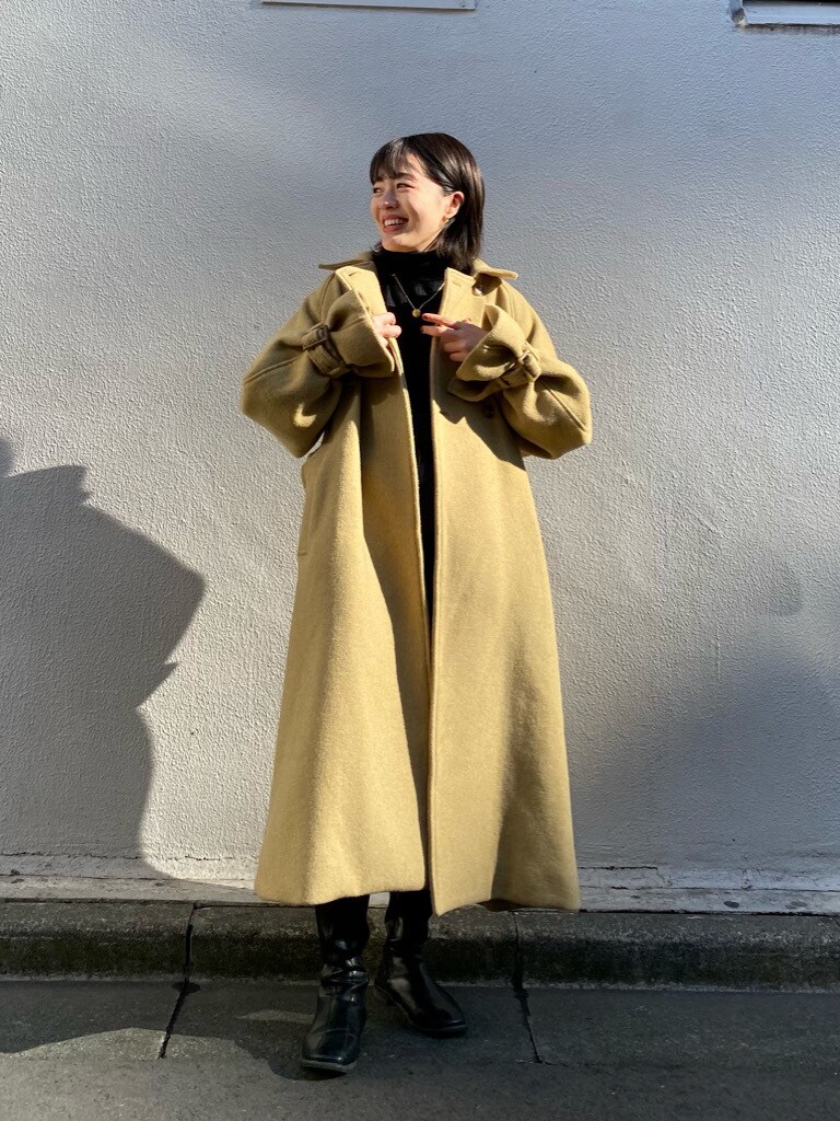イエロー系のステンカラーコートを着用したレディースの冬コーディネートの4枚目の写真