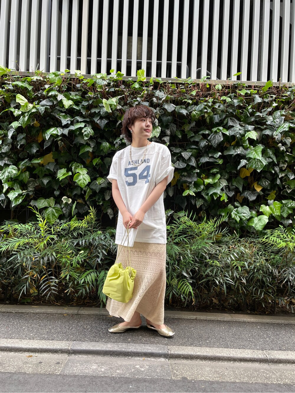 グリーン系のハンドバッグ、ホワイト系のTシャツ/カットソー、ベージュ系のスカートを着用したレディースの春コーディネートの4枚目の写真