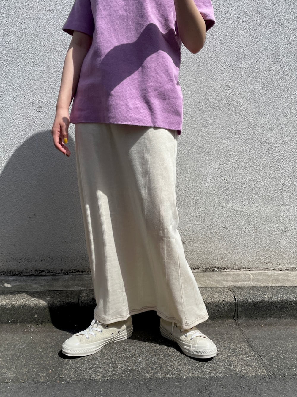 ホワイト系のスカート、パープル系のTシャツ/カットソー、ホワイト系のスニーカーを着用したレディースの春コーディネートの2枚目の写真