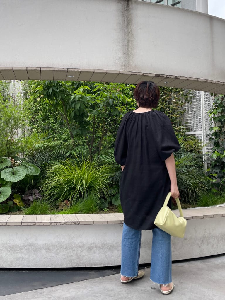 グリーン系のハンドバッグ、ブラック系のワンピース、ブルー系のデニムパンツを着用したレディースの春コーディネートの3枚目の写真