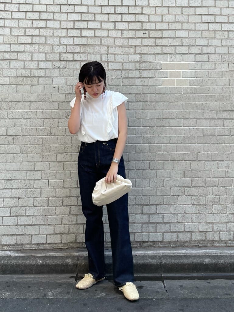 ブルー系のデニムパンツ、ホワイト系のクラッチバッグ、ホワイト系のTシャツ/カットソーを着用したレディースの夏コーディネートの2枚目の写真