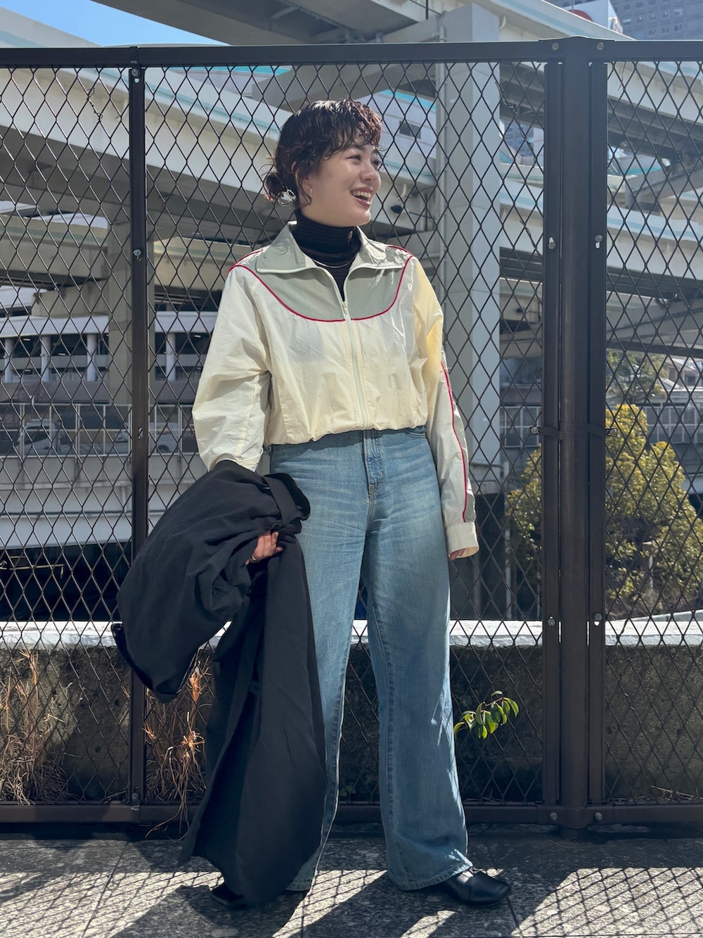 ブラック系のステンカラーコート、ホワイト系のブルゾンを着用したレディースの冬コーディネートの3枚目の写真