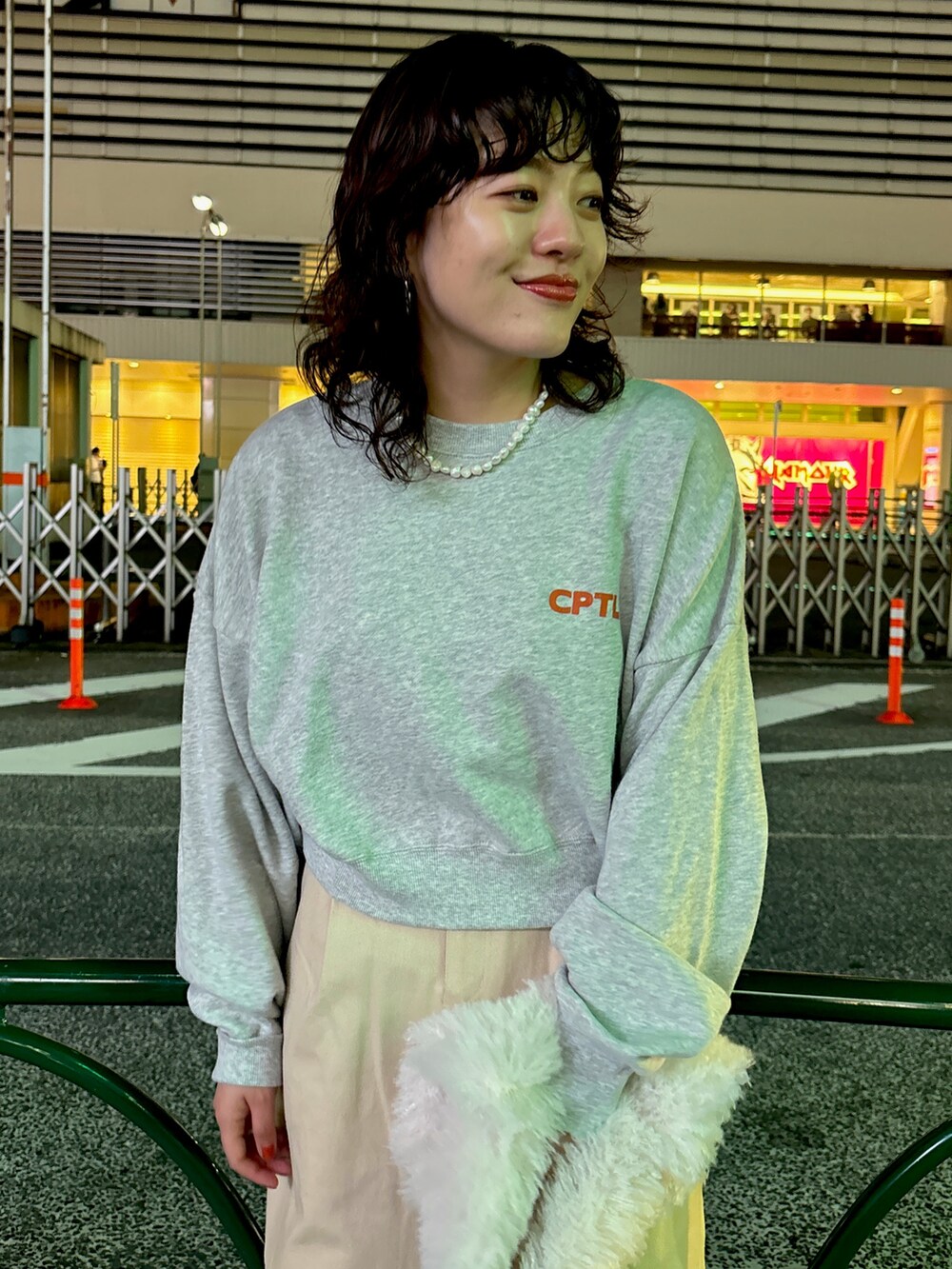 グレー系のスウェット、ベージュ系のスカート、ホワイト系のハンドバッグを着用したレディースの秋コーディネートの5枚目の写真