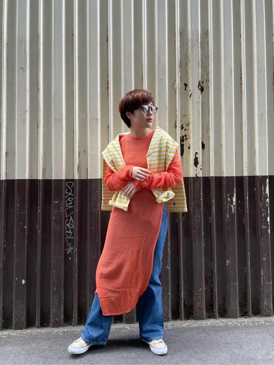 ブルー系のデニムパンツ、オレンジ系のワンピースを着用したレディースの春コーディネートの4枚目の写真