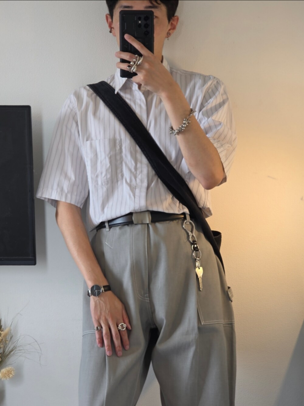 シルバー系のリング、ブラック系のキーホルダー、シルバー系のイヤーカフを着用したメンズの秋コーディネートの2枚目の写真