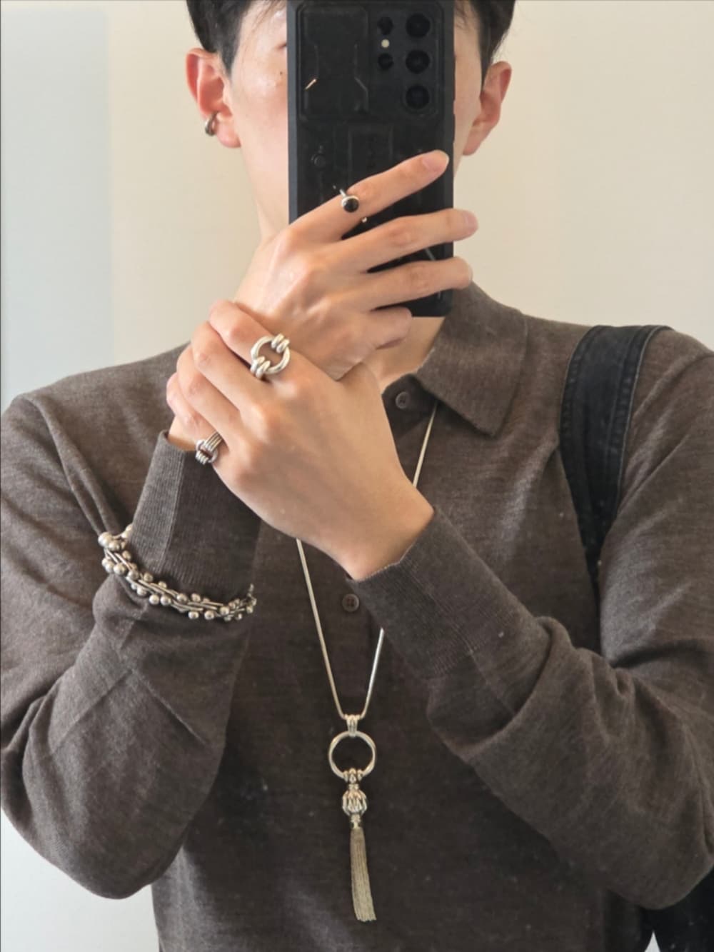 グレー系のニット/セーター、ブラック系のデニムパンツ、ブラック系のショルダーバッグを着用したメンズの秋コーディネートの2枚目の写真