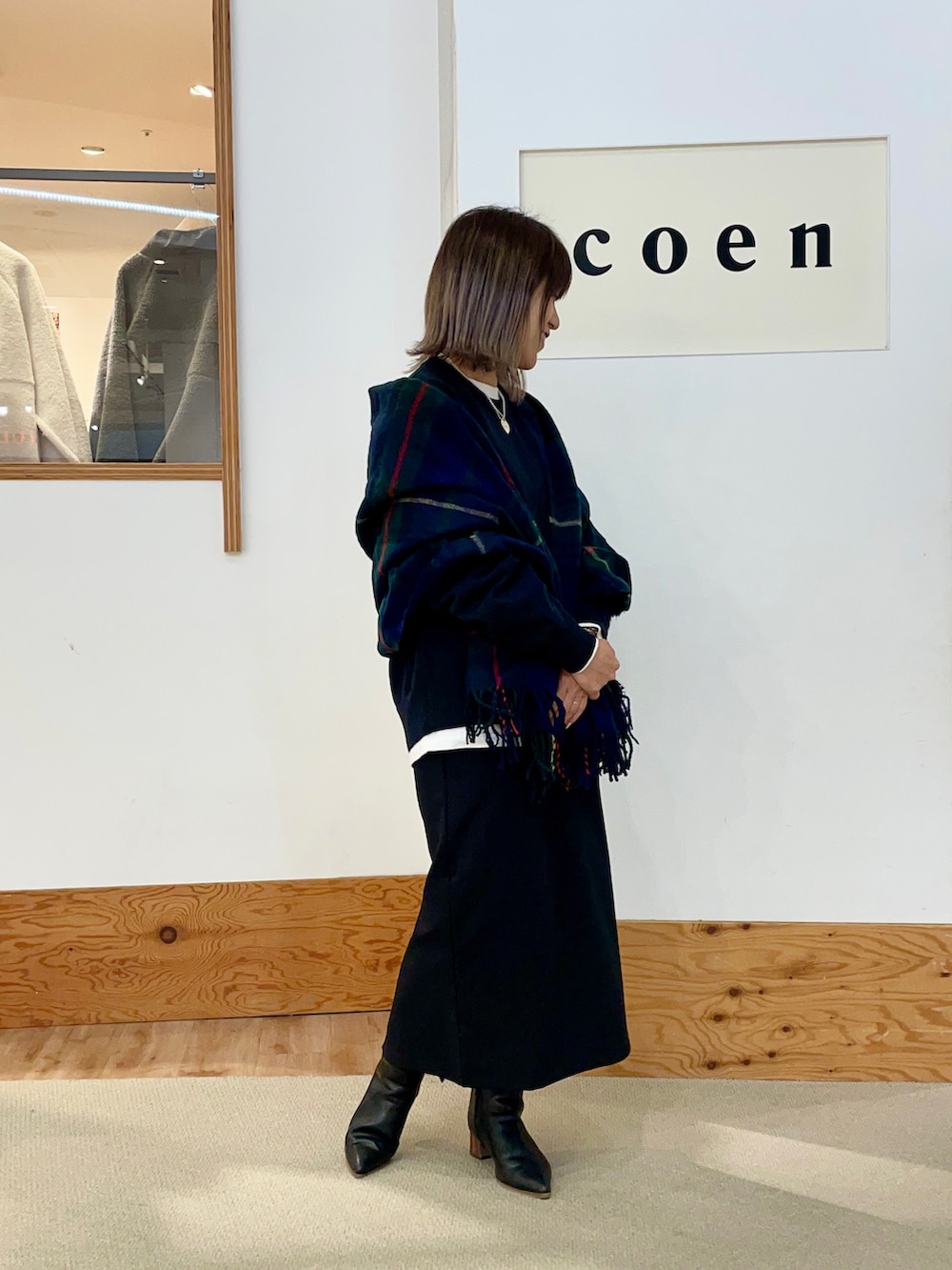 ブラック系のニット/セーター、ブラック系のスカート、ブラック系のブーツを着用したレディースの秋コーディネートの2枚目の写真