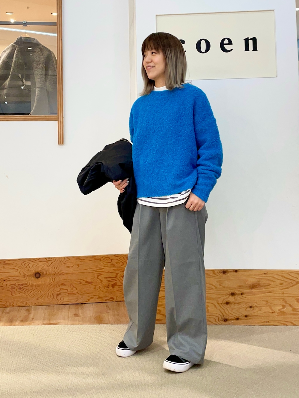 ブルー系のニット/セーター、グレー系のスラックス、ブラック系のMA-1を着用したレディースの冬コーディネートの2枚目の写真