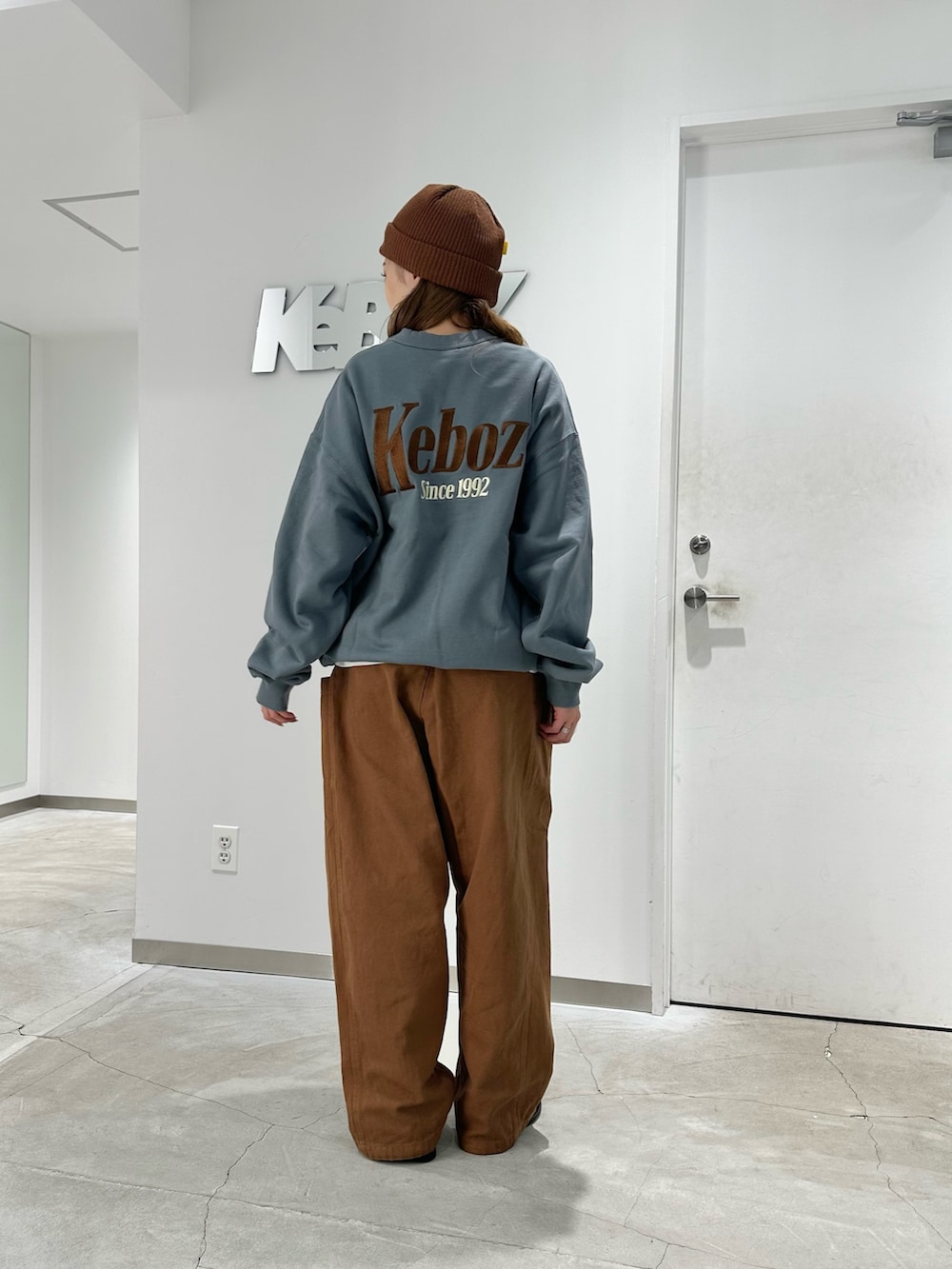 グレー系のスウェット、ブラウン系のカーゴパンツ、ブラウン系のニットキャップ/ビーニーを着用したレディースの秋コーディネートの3枚目の写真