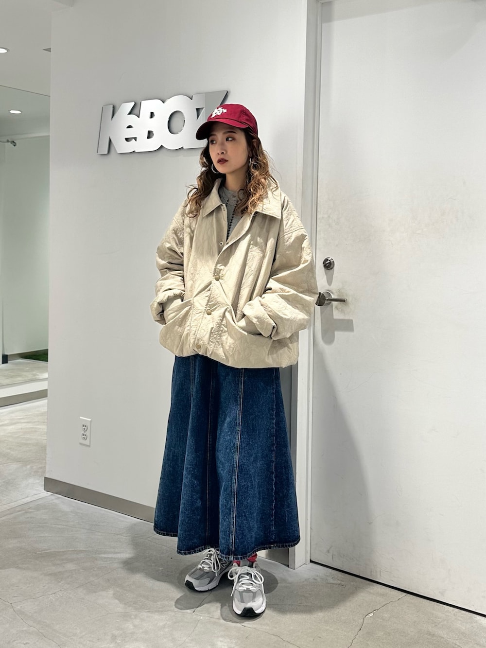 ベージュ系のブルゾン、ブルー系のデニムスカート、レッド系のキャップを着用したレディースの秋コーディネートの3枚目の写真