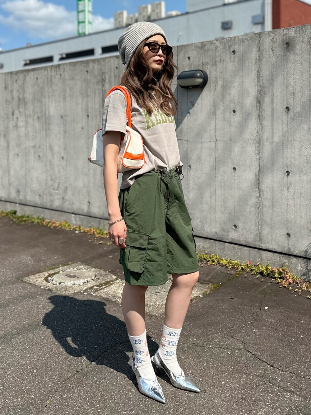 グリーン系のカーゴパンツ、オレンジ系のハンドバッグ、グレー系のTシャツ/カットソーを着用したレディースの秋コーディネートの2枚目の写真