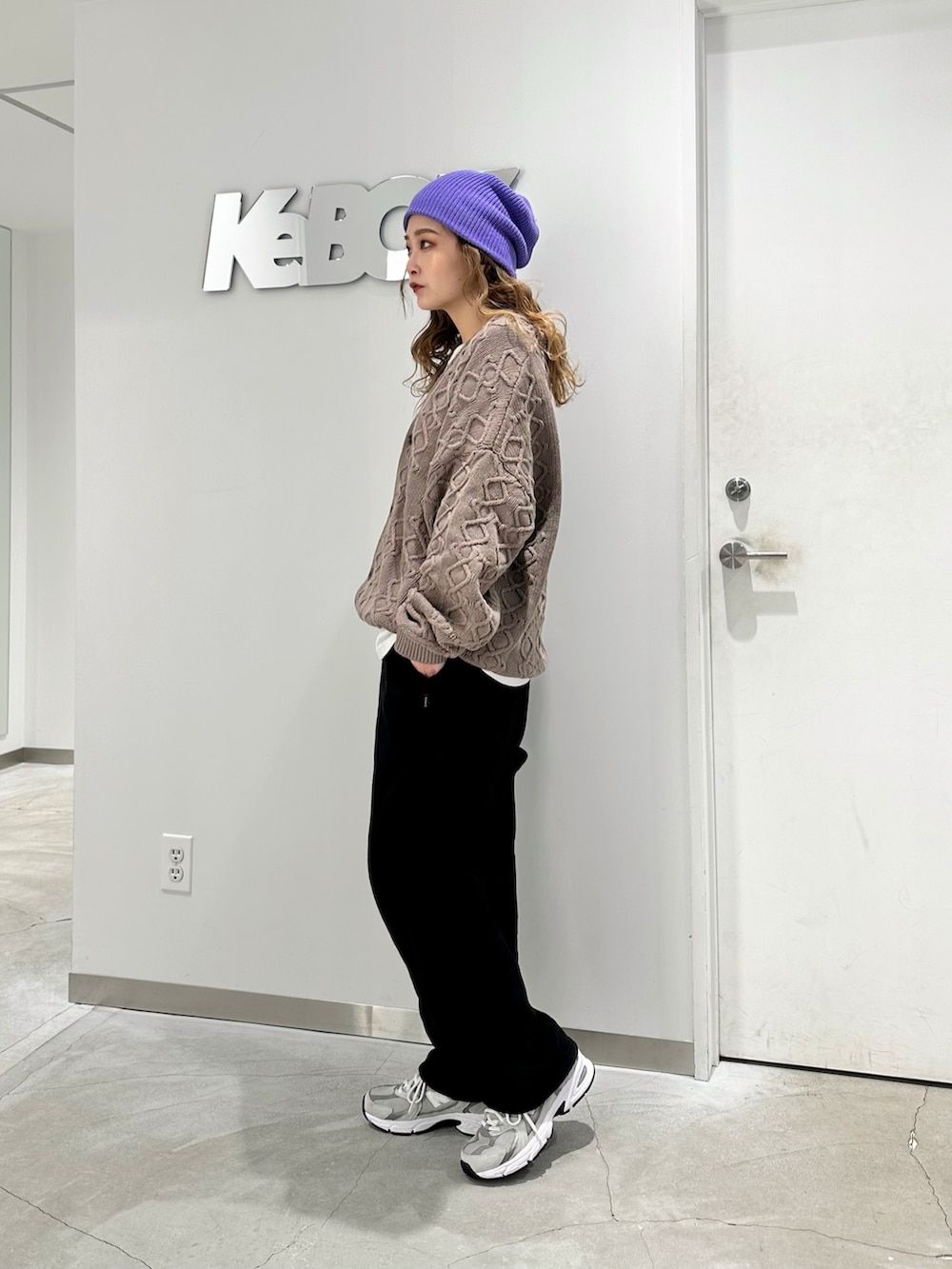 ブラウン系のカーディガン/ボレロ、ブラック系のスウェットパンツ、パープル系のニットキャップ/ビーニーを着用したレディースの冬コーディネートの2枚目の写真