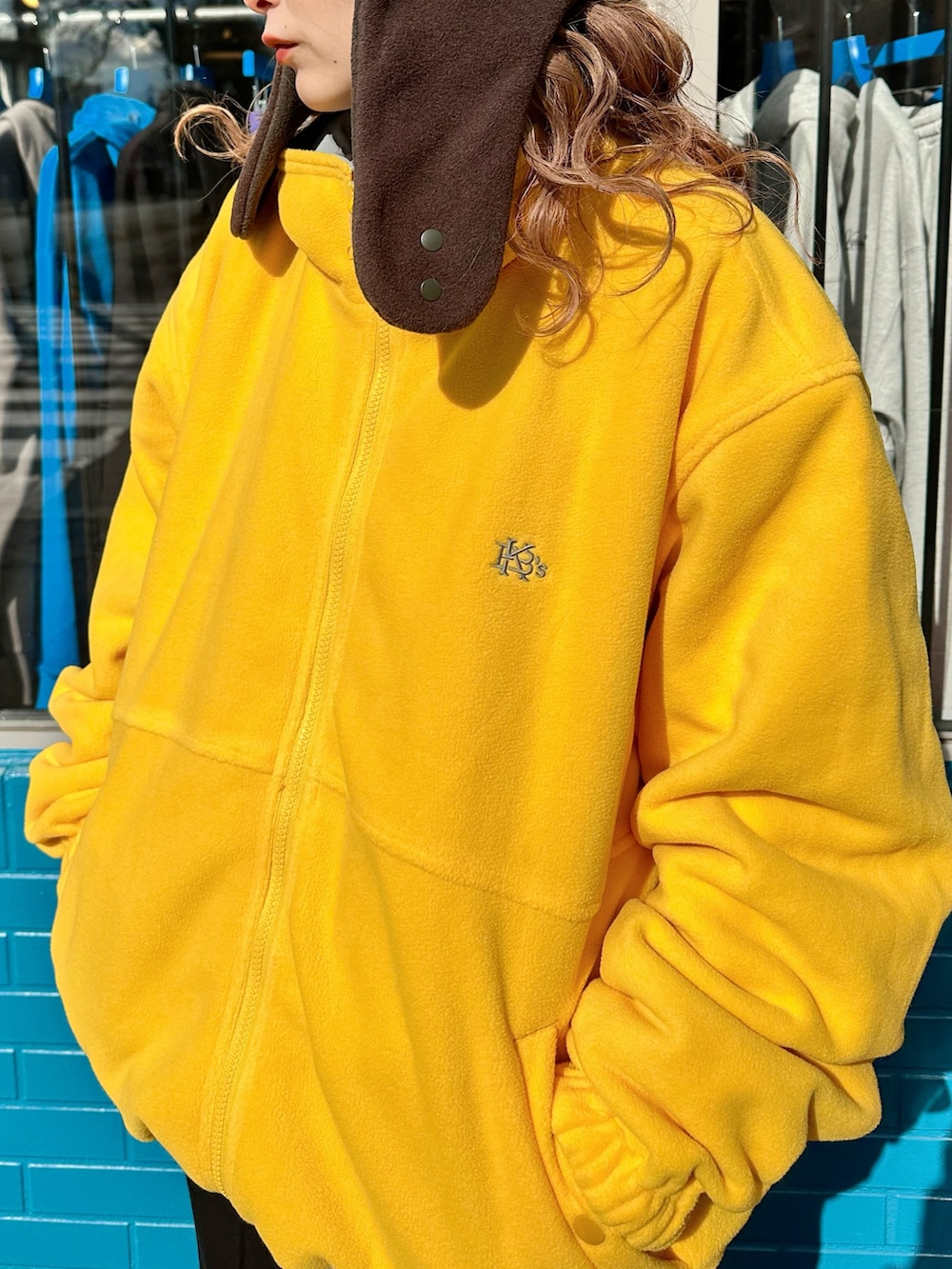 イエロー系のナイロンジャケット、ブラック系のスウェットパンツ、ブラウン系のハットを着用したレディースの秋コーディネートの5枚目の写真