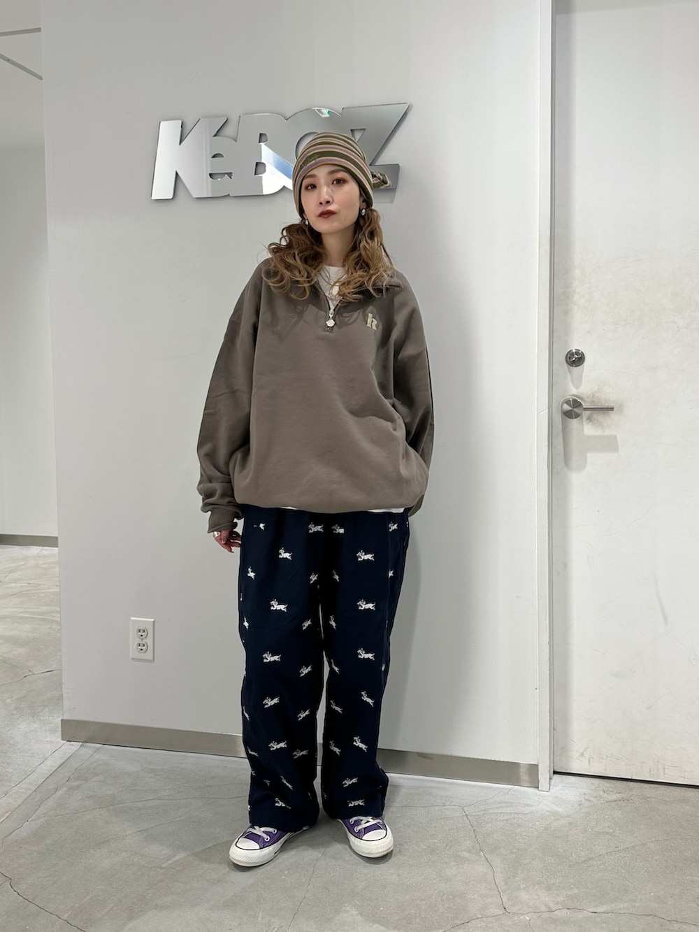 ブラウン系のスウェット、ブルー系のチノパンツ、グリーン系のニットキャップ/ビーニーを着用したレディースの冬コーディネートの2枚目の写真