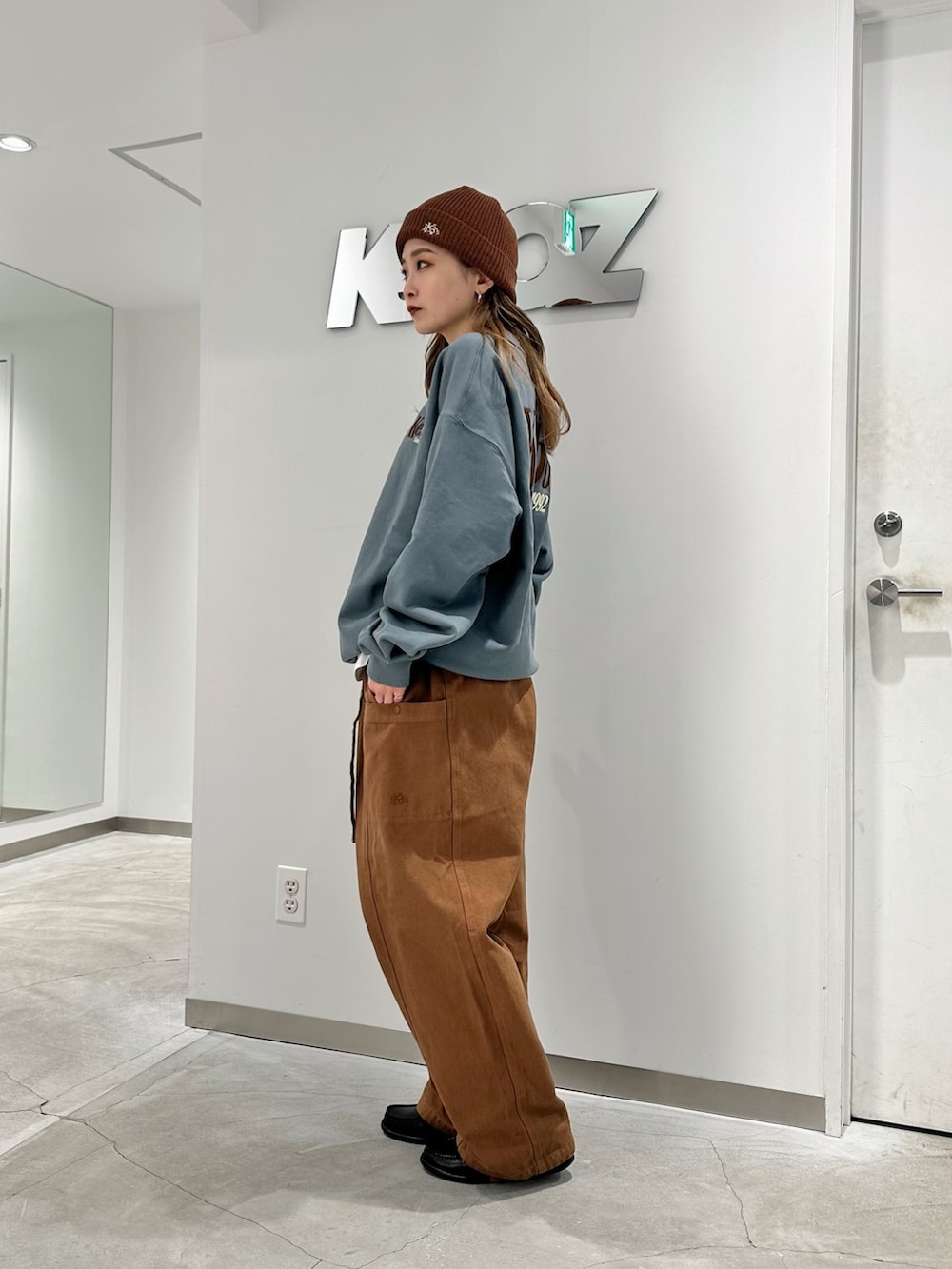 グレー系のスウェット、ブラウン系のカーゴパンツ、ブラウン系のニットキャップ/ビーニーを着用したレディースの秋コーディネートの2枚目の写真