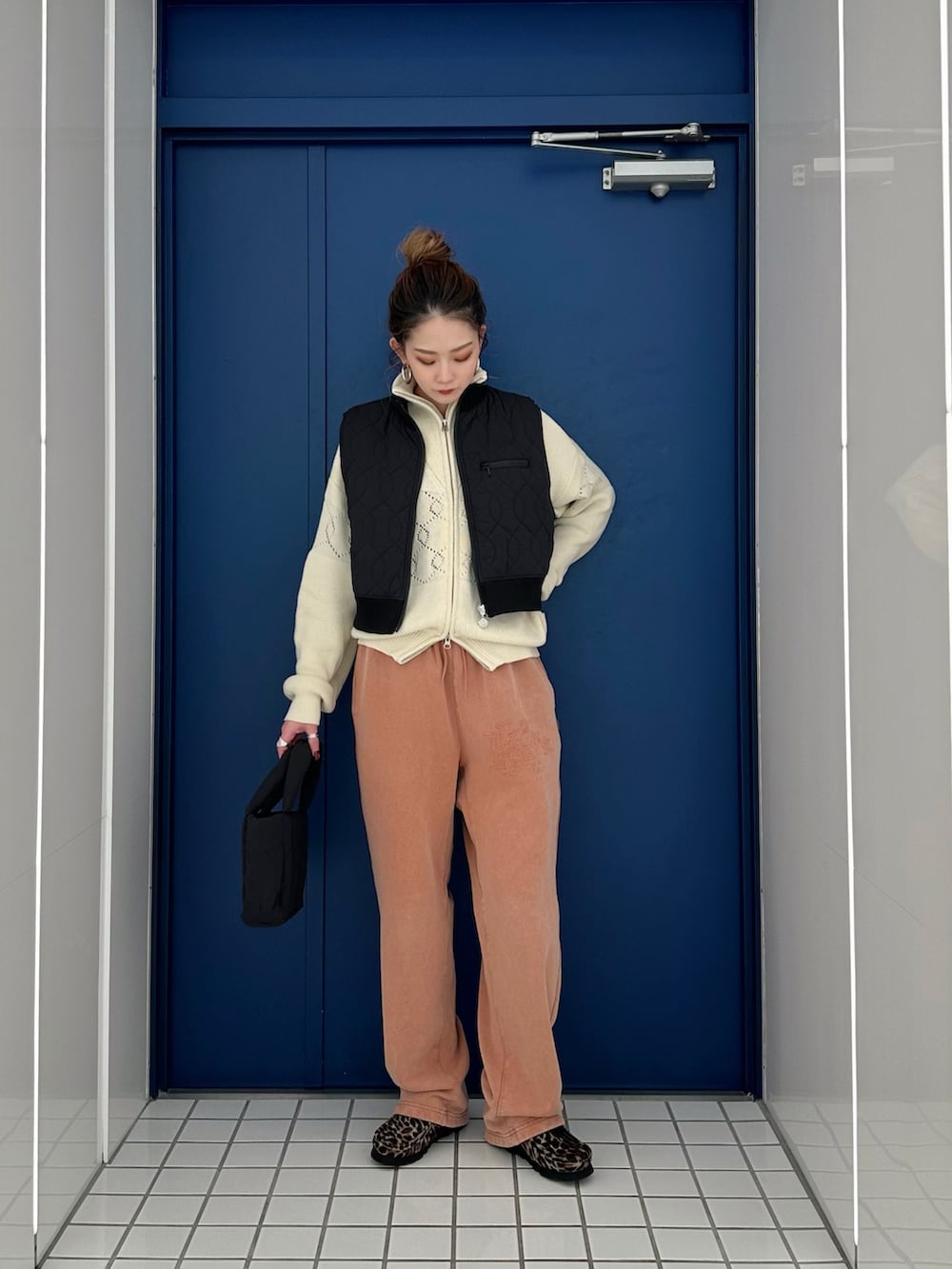 ホワイト系のブルゾン、ブラック系のベスト、ブラック系のハンドバッグを着用したレディースの冬コーディネートの2枚目の写真