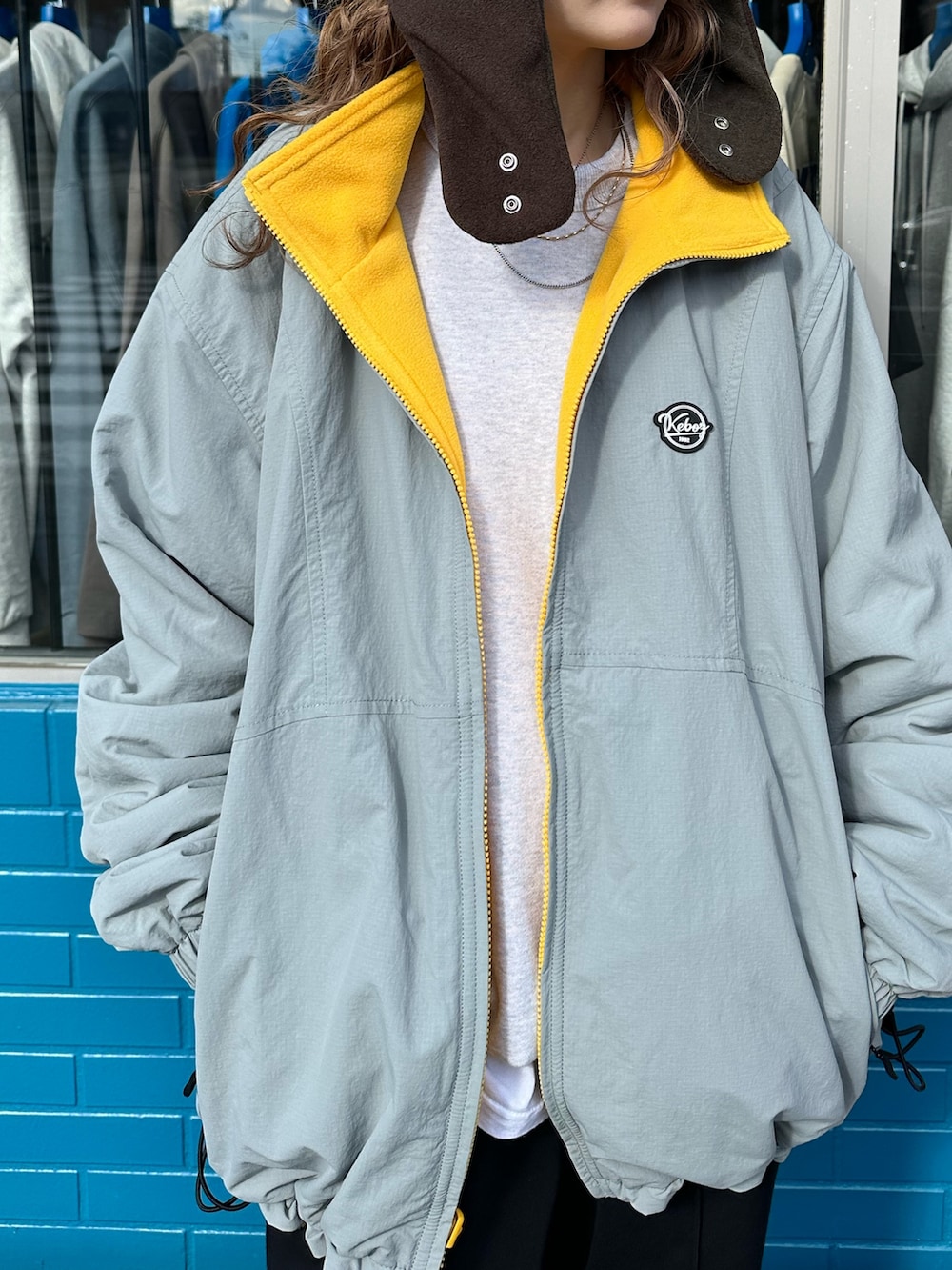 イエロー系のナイロンジャケット、ブラック系のスウェットパンツ、ブラウン系のハットを着用したレディースの秋コーディネートの6枚目の写真