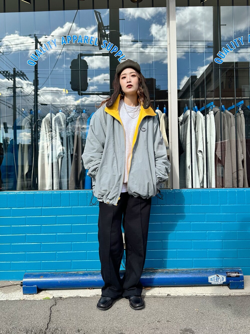 イエロー系のナイロンジャケット、ブラック系のスウェットパンツ、ブラウン系のハットを着用したレディースの秋コーディネートの3枚目の写真