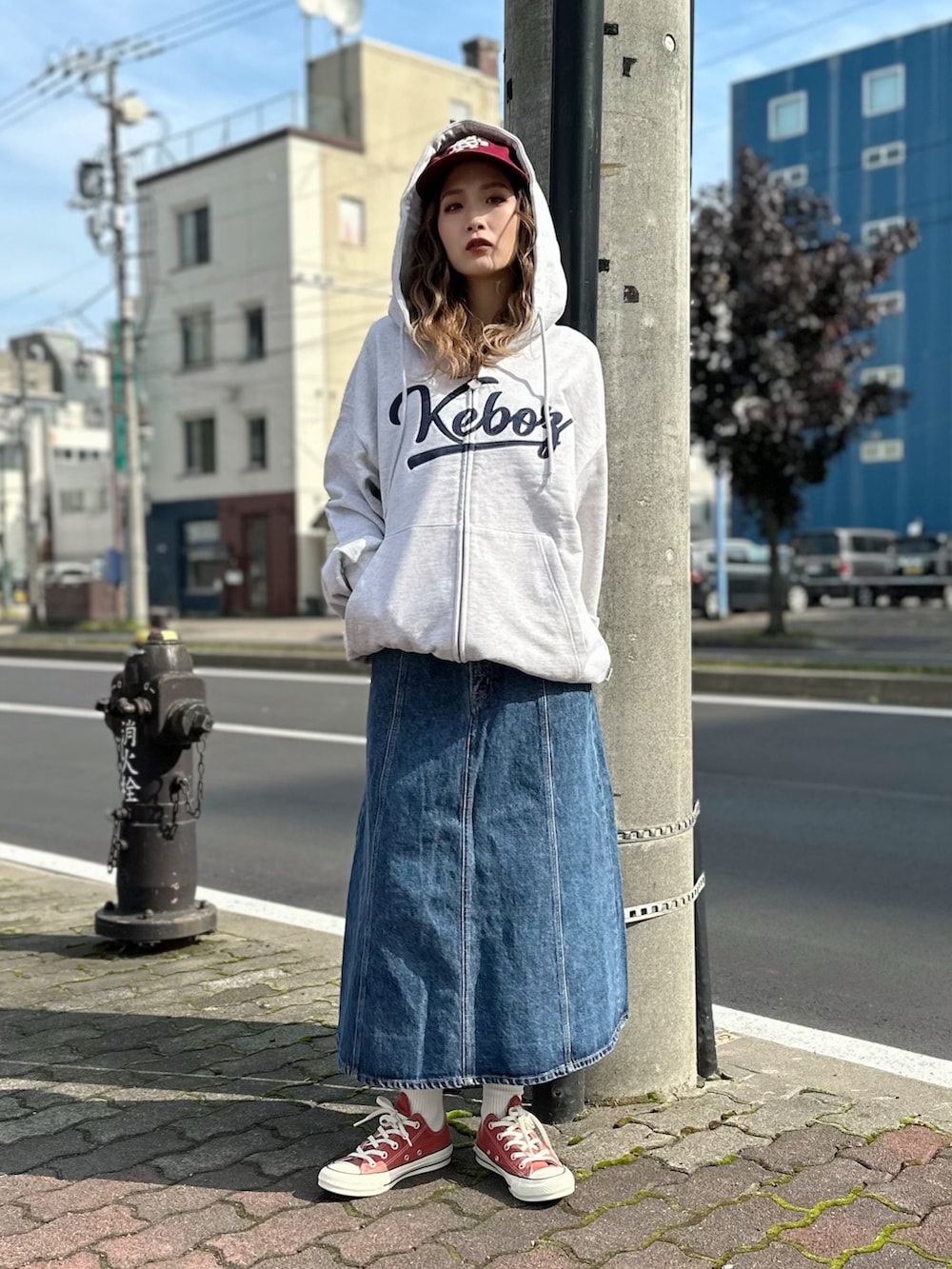 ブルー系のデニムスカート、グレー系のスウェット、レッド系のキャップを着用したレディースの秋コーディネートの3枚目の写真