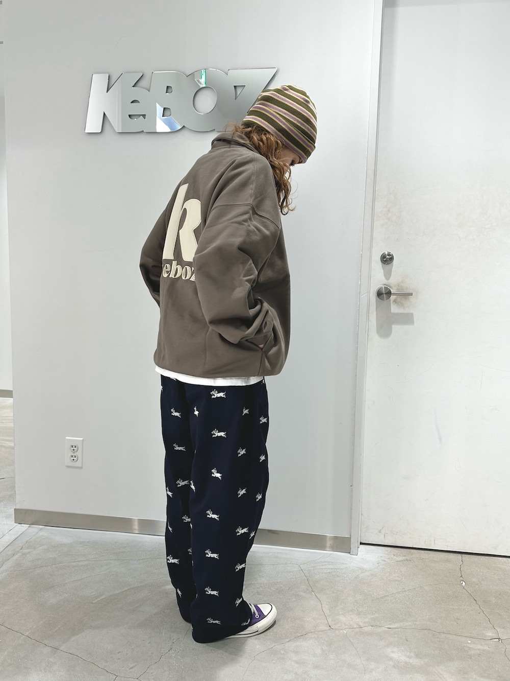 ブラウン系のスウェット、ブルー系のチノパンツ、グリーン系のニットキャップ/ビーニーを着用したレディースの冬コーディネートの3枚目の写真