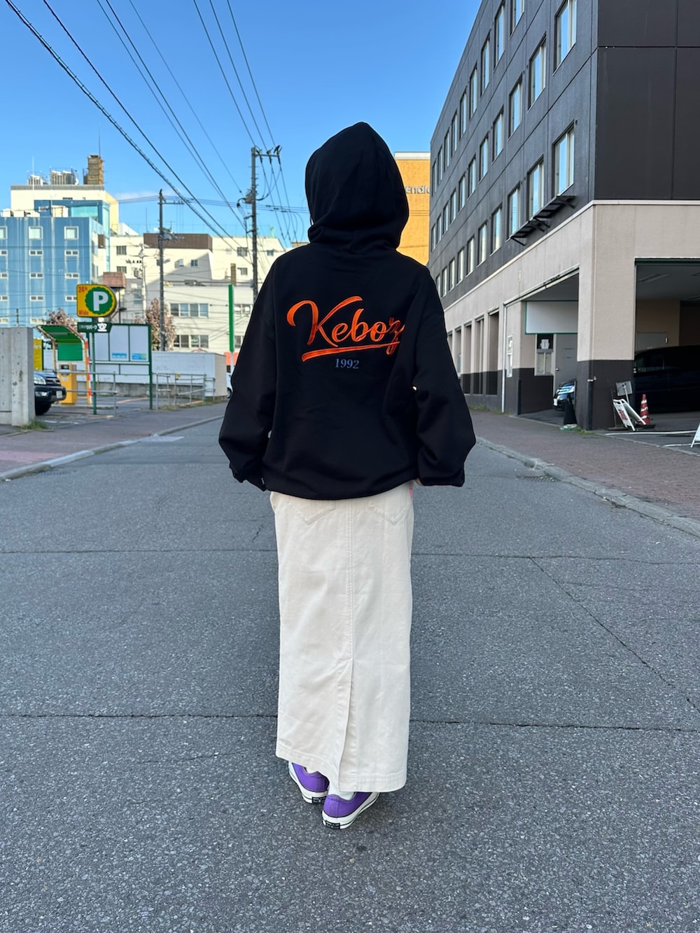 ベージュ系のスカート、ブラック系のパーカー、ブラック系のキャップを着用したレディースの秋コーディネートの4枚目の写真