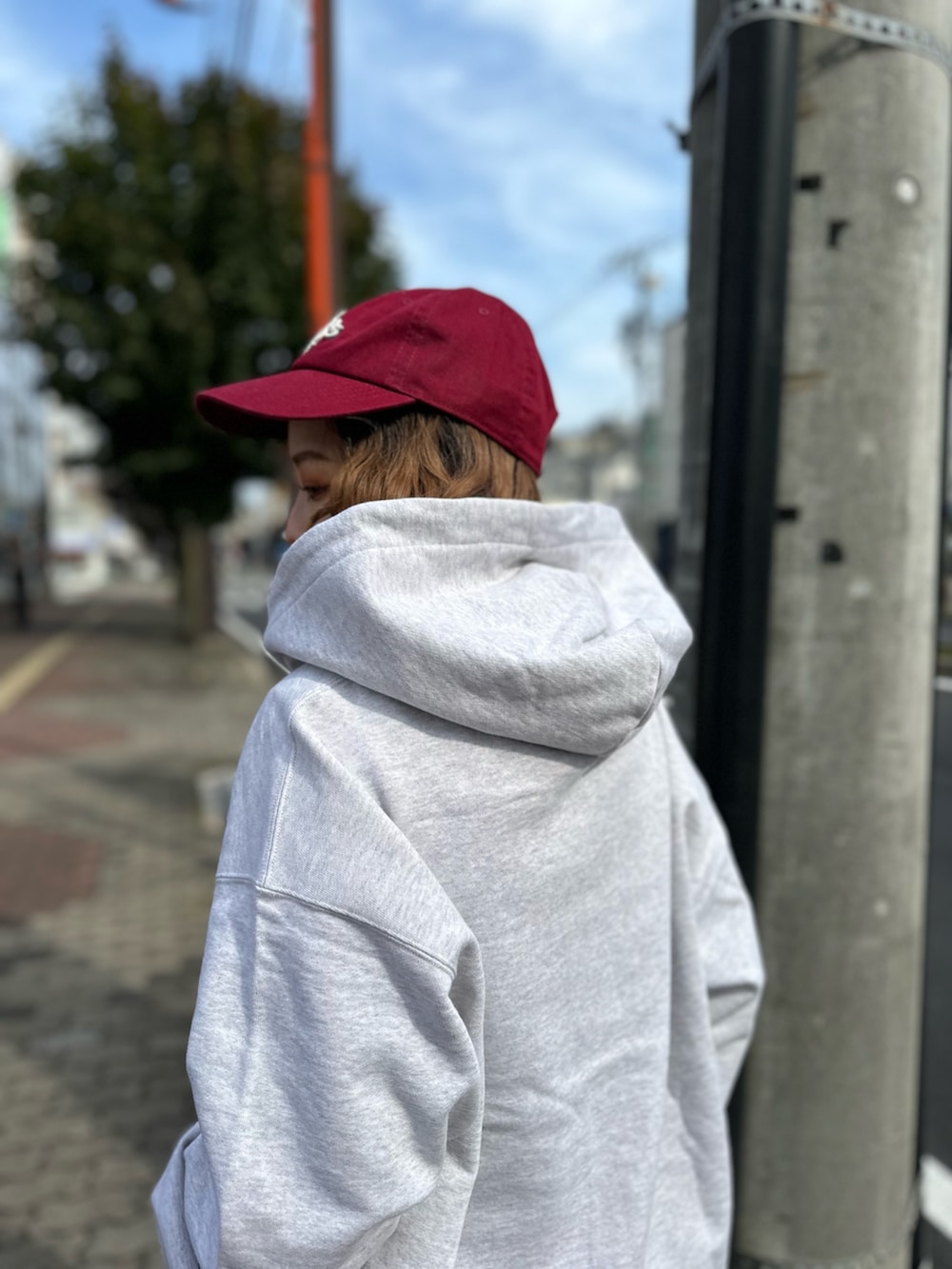 ブルー系のデニムスカート、グレー系のスウェット、レッド系のキャップを着用したレディースの秋コーディネートの4枚目の写真