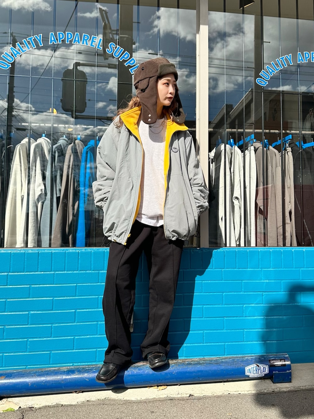 イエロー系のナイロンジャケット、ブラック系のスウェットパンツ、ブラウン系のハットを着用したレディースの秋コーディネートの4枚目の写真
