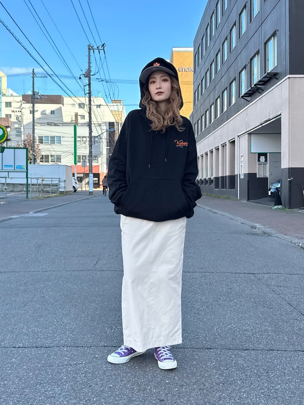 ベージュ系のスカート、ブラック系のパーカー、ブラック系のキャップを着用したレディースの秋コーディネートの3枚目の写真