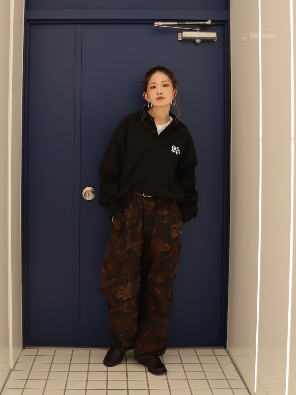 ブラック系のポロシャツ、その他のカーゴパンツを着用したレディースの春コーディネートの2枚目の写真