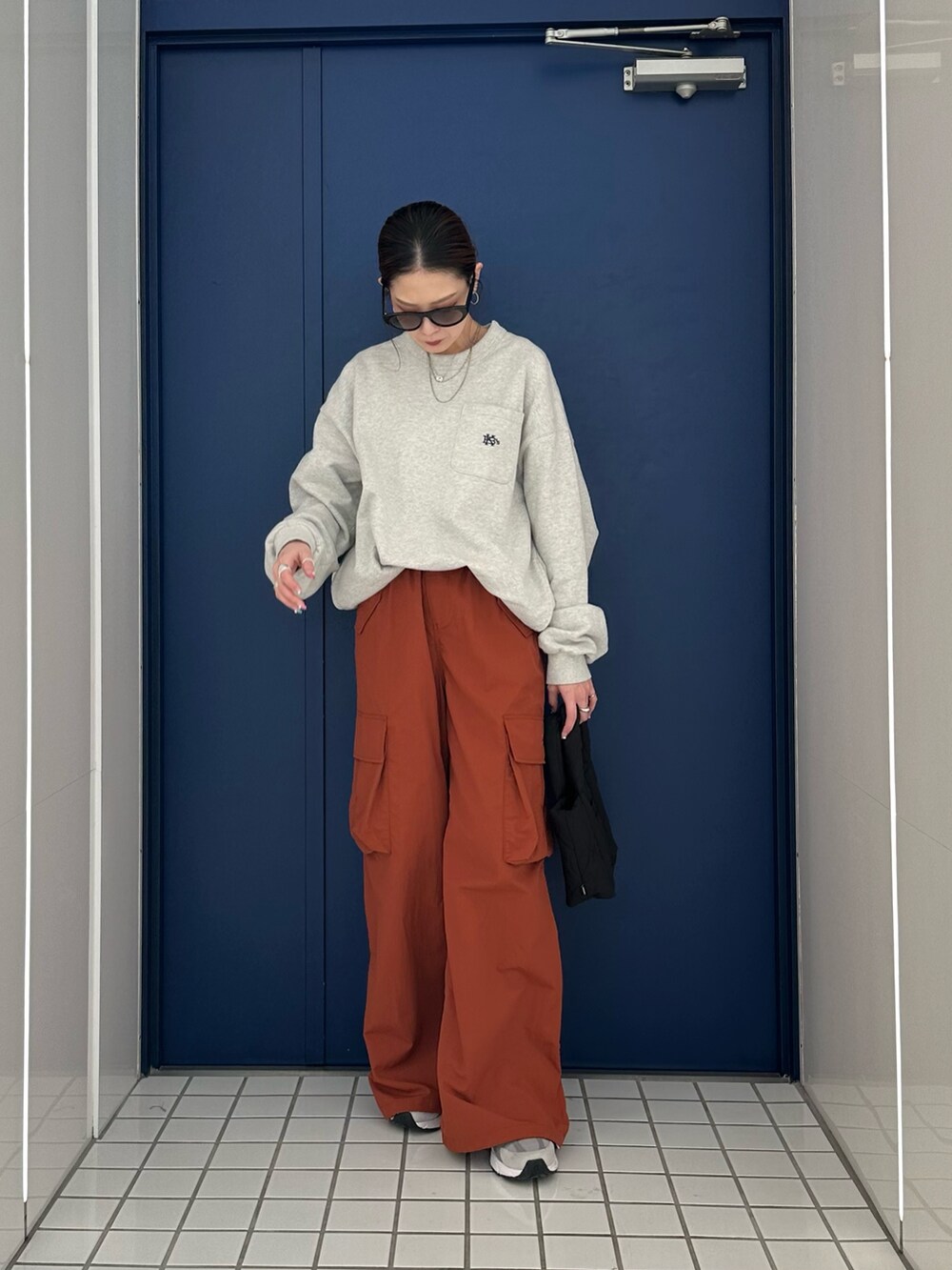 グレー系のスウェット、レッド系のカーゴパンツ、ブラック系のハンドバッグを着用したレディースの冬コーディネートの2枚目の写真