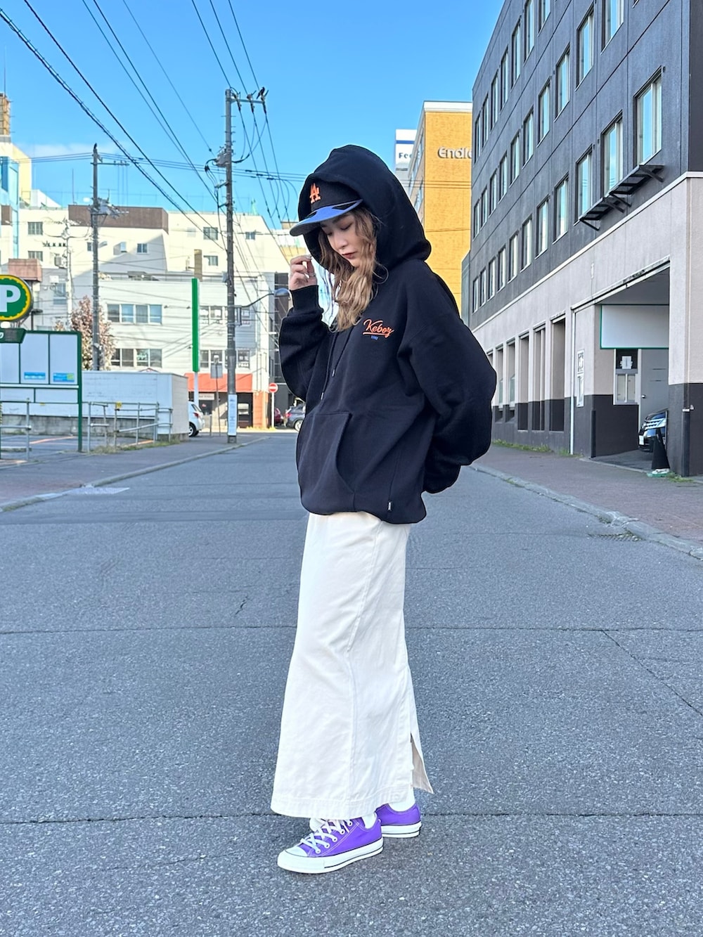 ベージュ系のスカート、ブラック系のパーカー、ブラック系のキャップを着用したレディースの秋コーディネートの2枚目の写真