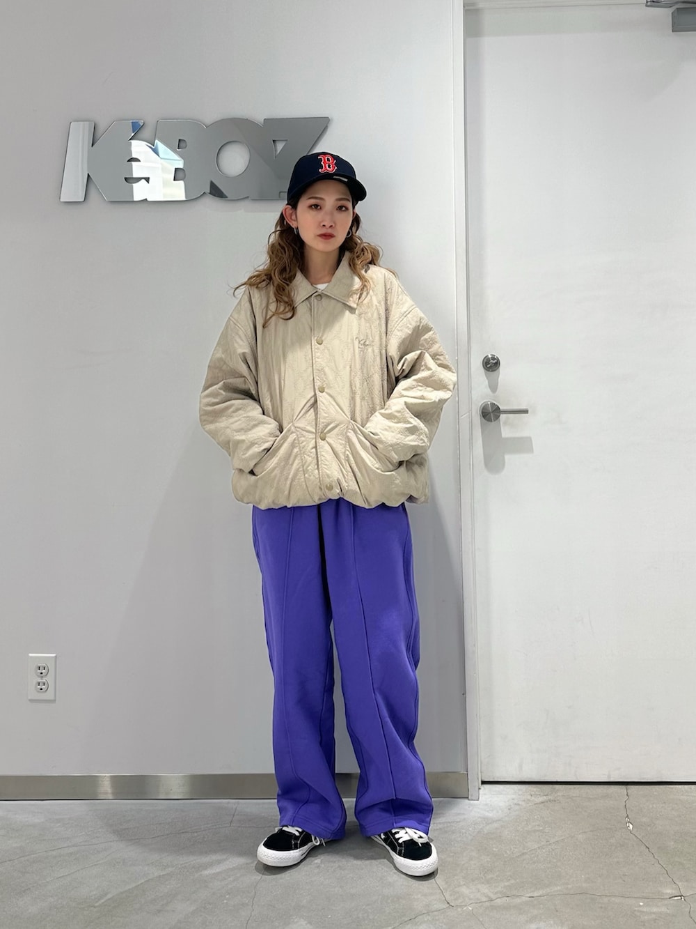 ベージュ系のブルゾン、パープル系のスウェットパンツを着用したレディースの冬コーディネートの2枚目の写真