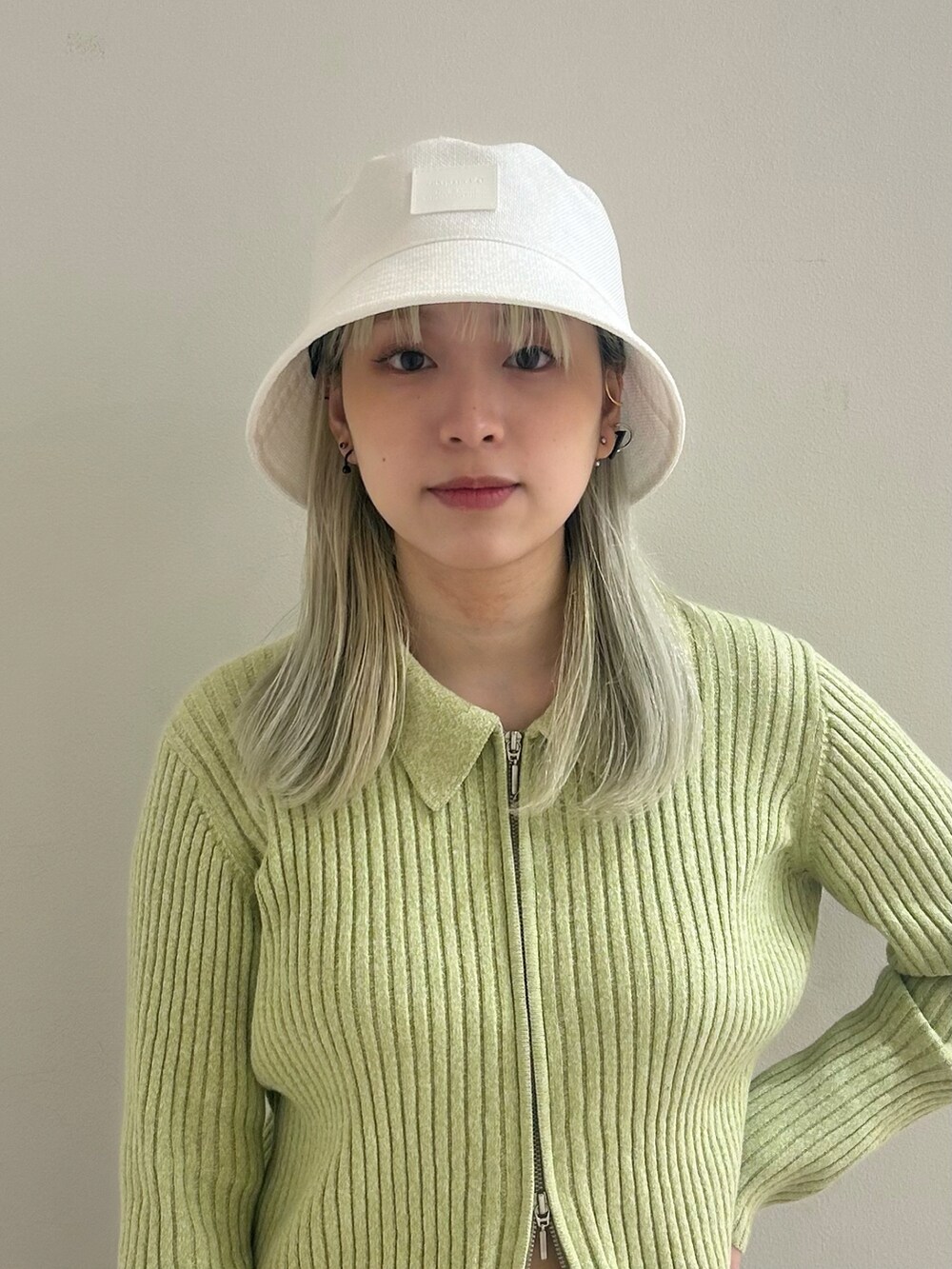 グリーン系のトップス、シルバー系のブーツ、グレー系のパンツを着用したレディースの春コーディネートの2枚目の写真