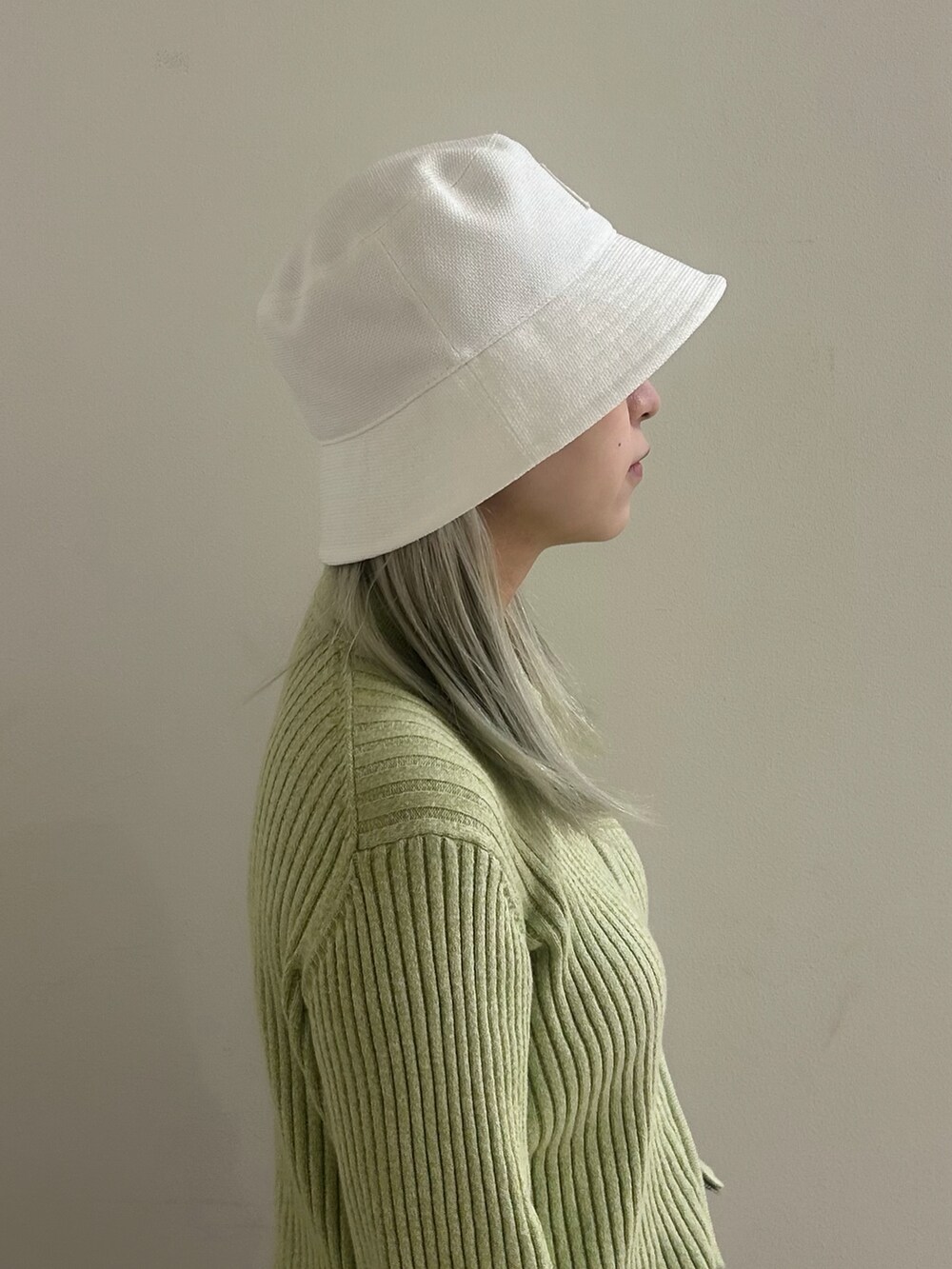 グリーン系のトップス、シルバー系のブーツ、グレー系のパンツを着用したレディースの春コーディネートの3枚目の写真