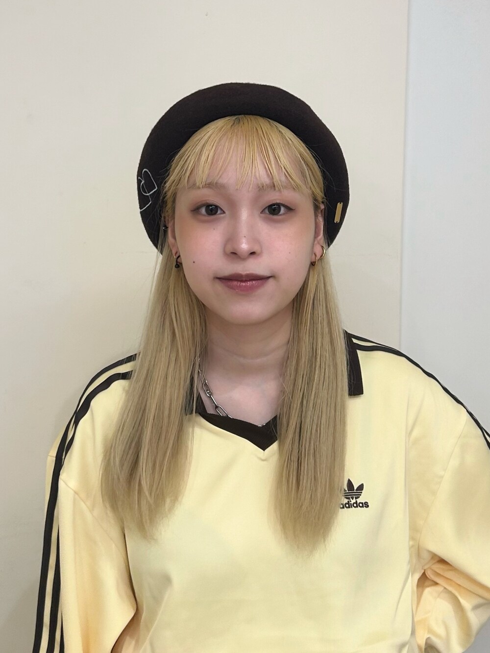 イエロー系のトップス、ベージュ系のスカート、ブルー系のスニーカーを着用したレディースの秋コーディネートの2枚目の写真