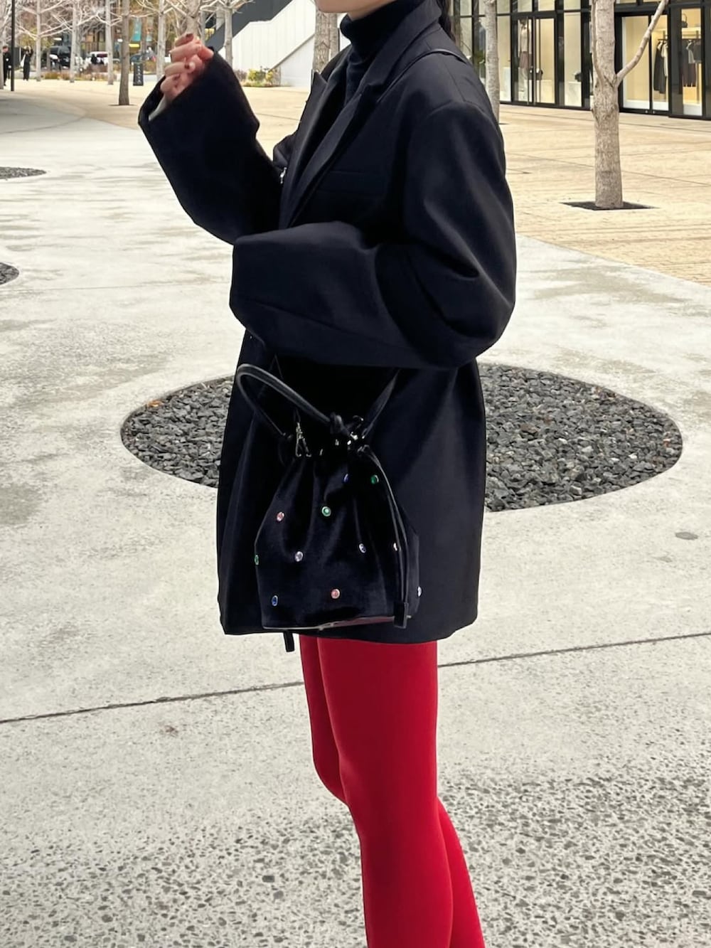 ブラック系のテーラードジャケット、ブラック系のハンドバッグ、ブラック系のブーツを着用したレディースの春コーディネートの4枚目の写真