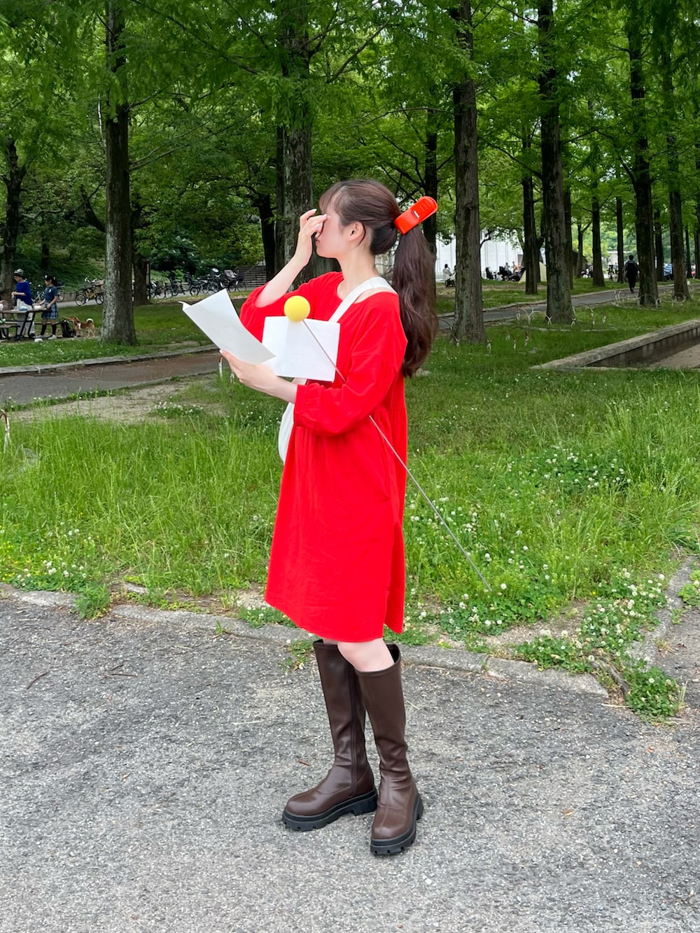 ホワイト系のショルダーバッグ、レッド系のワンピース、ブラウン系のブーツを着用したレディースの夏コーディネートの2枚目の写真