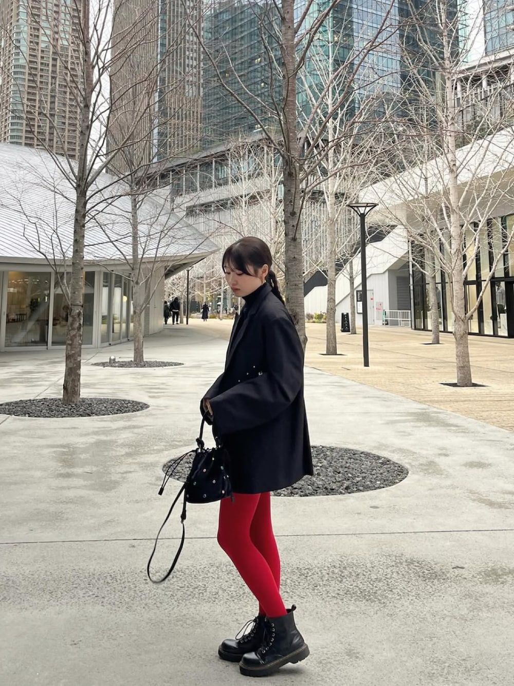 ブラック系のテーラードジャケット、ブラック系のハンドバッグ、ブラック系のブーツを着用したレディースの春コーディネートの3枚目の写真